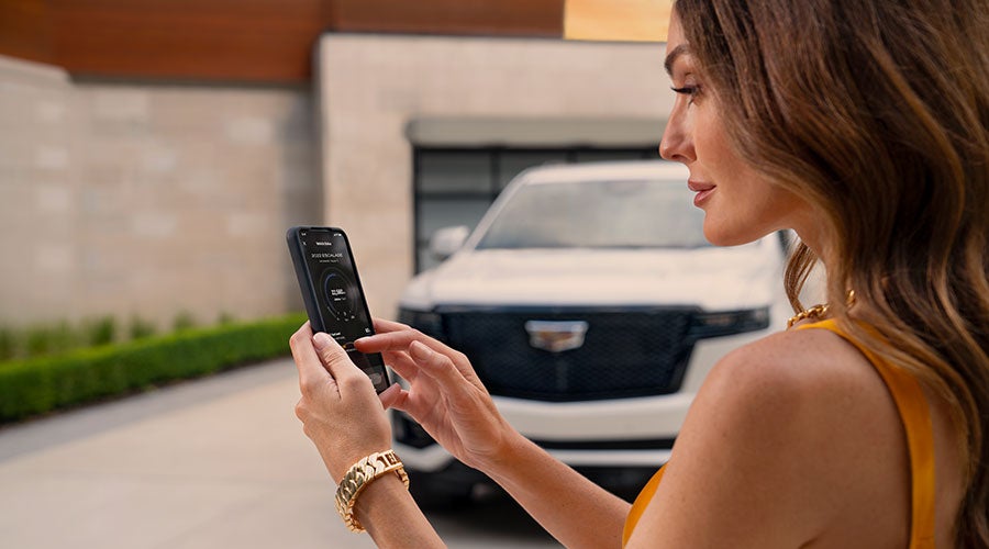 Woman holding phone with Escalade and building in background.